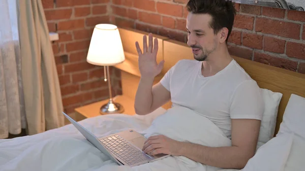 Junger Mann beim Videochat auf Laptop im Bett — Stockfoto