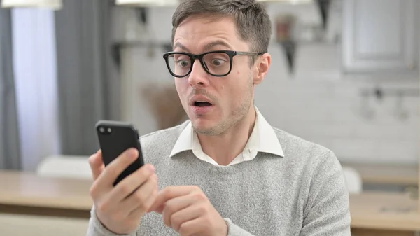 Hombre joven reaccionando a la pérdida en el Smartphone —  Fotos de Stock