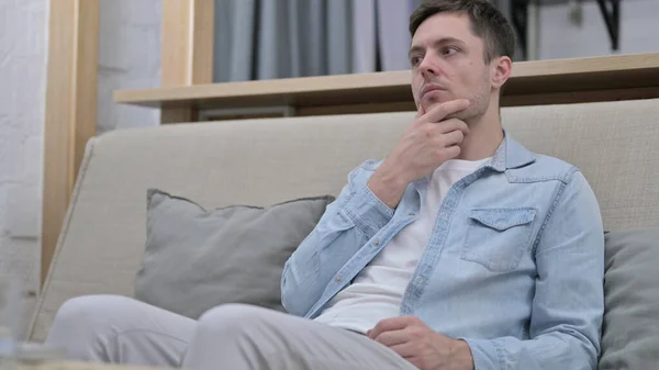 Curious Young Man Thinking while Sitting on Sofa — Stock Photo, Image