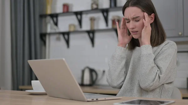 Młoda kobieta z bólem głowy i pracy na laptopie — Zdjęcie stockowe