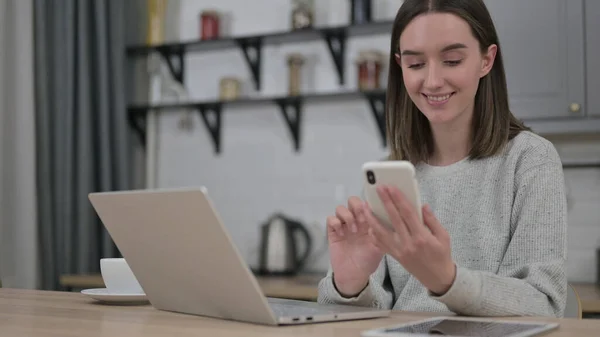 Mladá žena pomocí Smartphone v obývacím pokoji — Stock fotografie