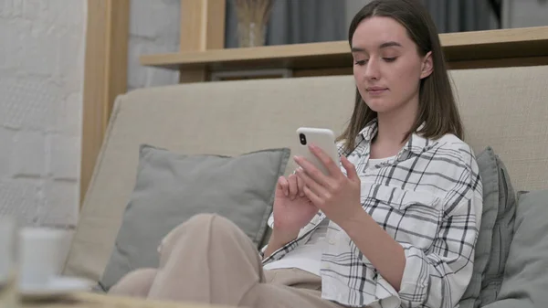 Bela jovem mulher usando smartphone em casa — Fotografia de Stock