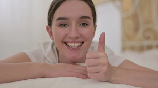 Крупним планом весела молода жінка робить великі пальці в ліжку — стокове фото