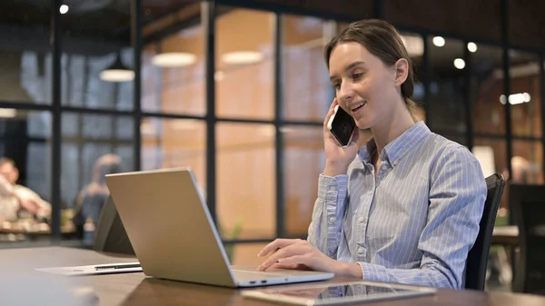 Jonge vrouw praten op telefoon en het gebruik van laptop — Stockfoto