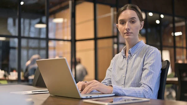 Femme travaillant sur ordinateur portable regardant vers la caméra — Photo