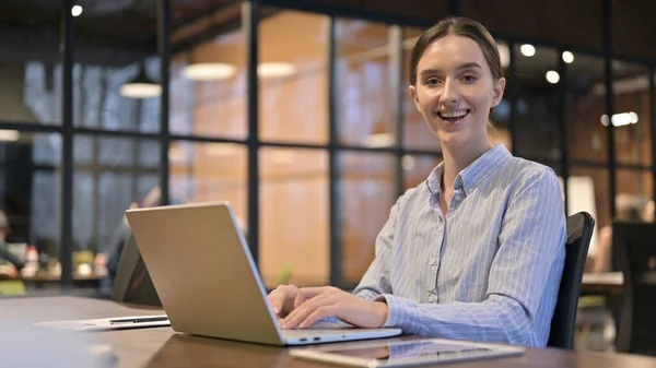 Žena s úsměvem směrem k fotoaparátu při práci na notebooku — Stock fotografie