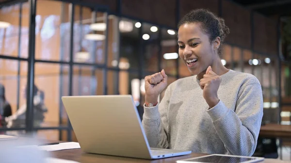 Excited African Woman Celebrating Success on Laptop