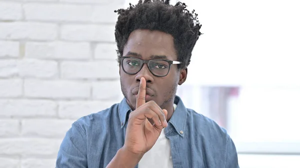 Jonge Afrikaanse man putting vinger op lippen — Stockfoto