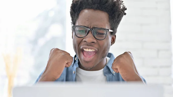 Retrato do jovem homem africano comemorando no laptop — Fotografia de Stock