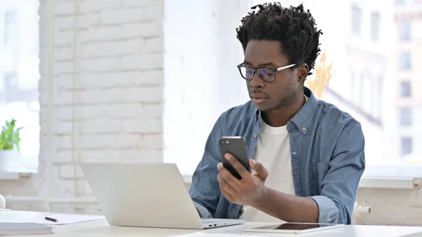 スマートフォンやノートパソコンを使う若いアフリカ人男性 — ストック写真