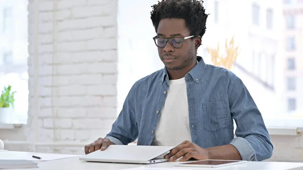 Ung afrikansk man kom tillbaka till jobbet, öppna laptop — Stockfoto