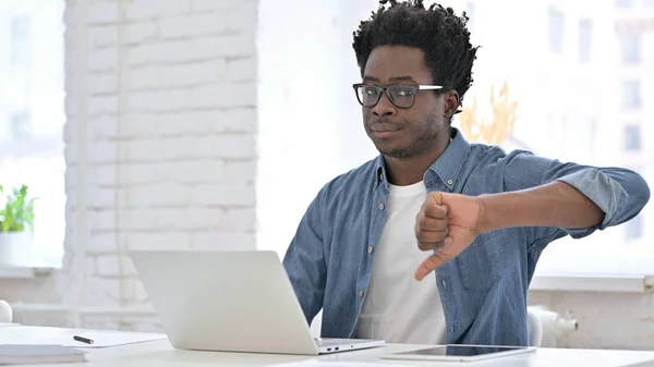 Mladý Afričan pracuje a ukazuje palce dolů — Stock fotografie