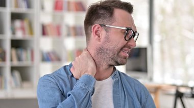 Gözlüklü genç adam boyun ağrısı çekiyor.