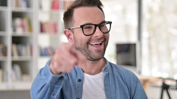 Feliz joven con gafas apuntando con el dedo a la cámara —  Fotos de Stock