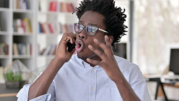 Agresivní africký muž mluví na smartphonu — Stock fotografie