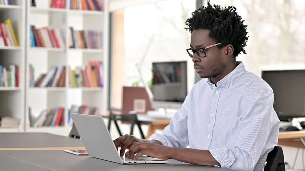 Fokuserad afrikansk affärsman som arbetar på laptop — Stockfoto