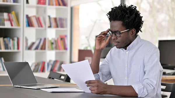 Fokuserad afrikansk man gör pappersarbete i Office — Stockfoto