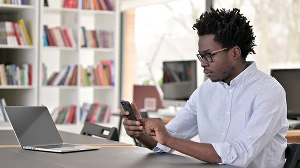 African Man Browsing Internet on Smartphone at Work — Stok fotoğraf
