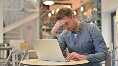 Kafede dizüstü bilgisayar kullanan sıradan bir adam.