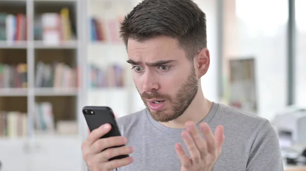 Jeune homme sous le choc regardant sur Smartphone — Photo