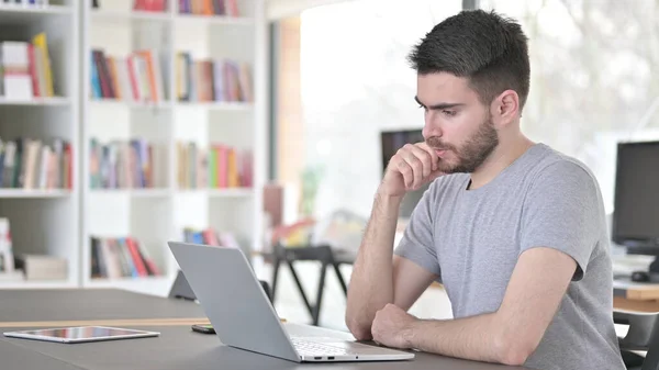 Pensive Young Man Olvasás a laptopon az irodában — Stock Fotó