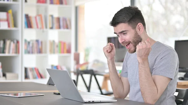 Succesvolle jongeman viert feest op laptop in kantoor — Stockfoto