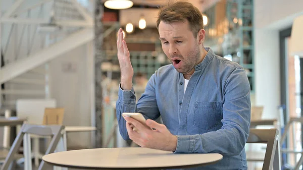 Schockierter Mann reagiert auf Fehlschlag mit Smartphone im Café — Stockfoto