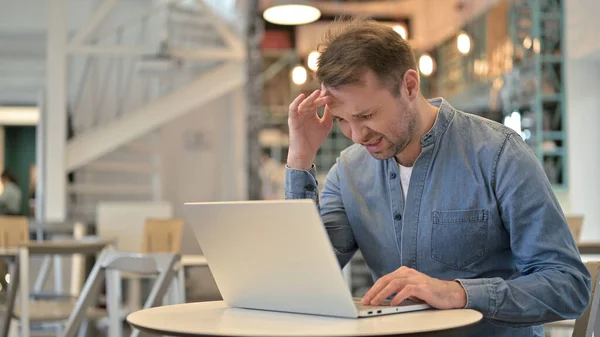 Lässiger Mann mit Kopfschmerzen benutzt Laptop im Café — Stockfoto