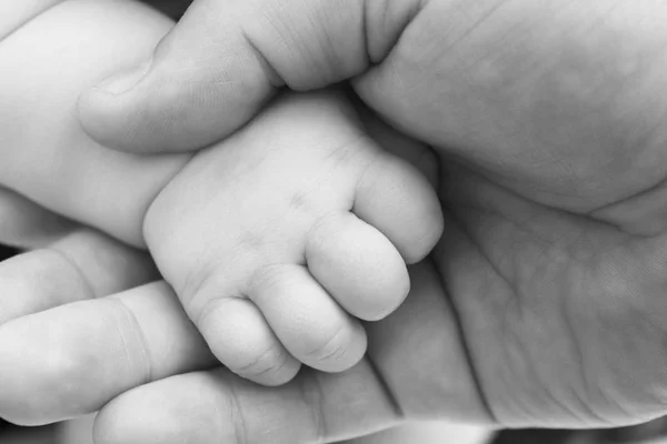 La mano del niño pequeño en la mano de los padres adultos primer plano / foto en blanco y negro en estilo retro —  Fotos de Stock