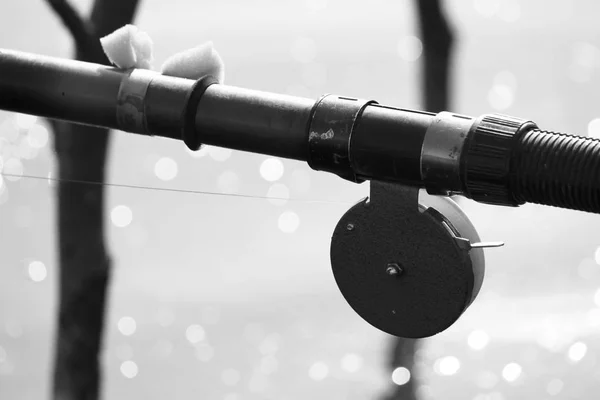 Foto in bianco e nero con vecchia canna da pesca in stile retrò primo piano sullo sfondo del lago e bokeh — Foto Stock