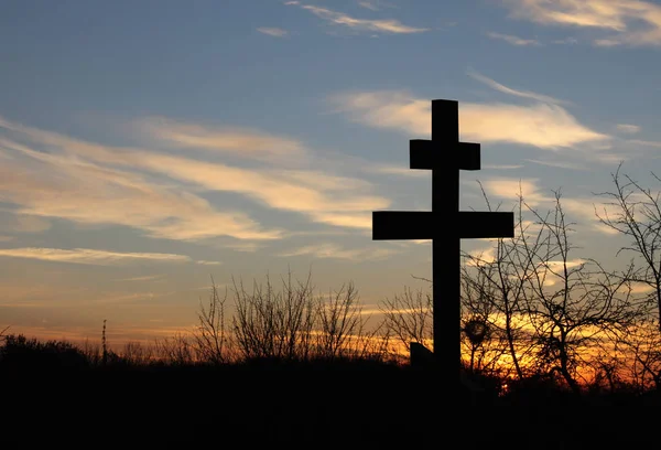 Christian cross on blue sky background at sunset