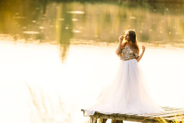 Retrato en un vestido al atardecer cerca de un lago — Foto de Stock