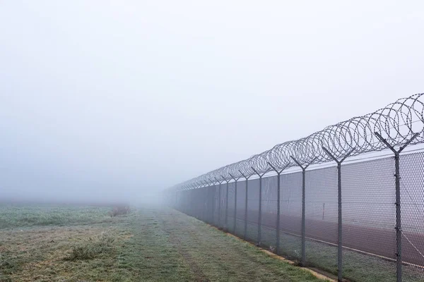 Lange grens hek in de mist — Stockfoto