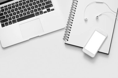 Dizüstü bilgisayar, telefon, defter ve beyaz arka plan üzerinde kulaklık