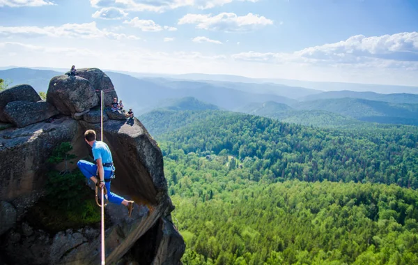 Slacklining, man walks the line at high altitude above the forest