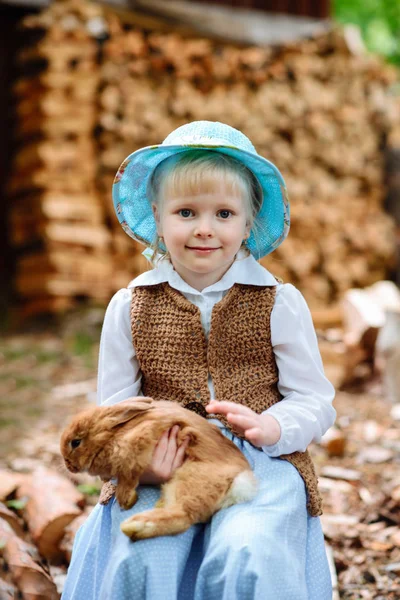 Blonde fille dans le chapeau tenant un lapin — Photo