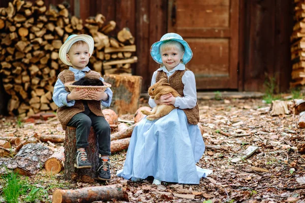 Niño y niña en el pueblo jugando con los conejos — Foto de Stock