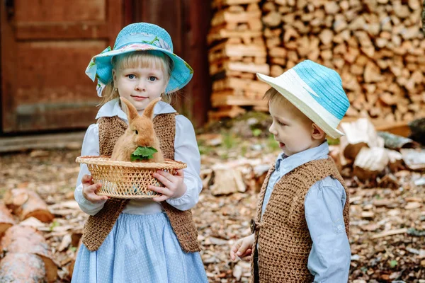 Garçon et fille dans le village jouer avec les lapins — Photo