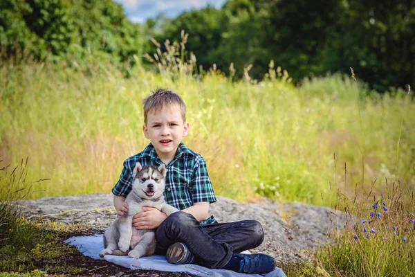 O menino com filhote de cachorro husky — Fotografia de Stock