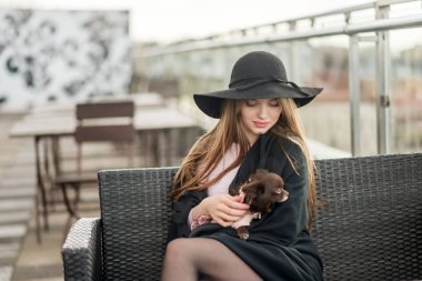 Kız bir siyah şapka çapında ekledi ve restoranın terasında oturup pelerin