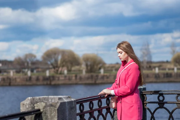 Das Mädchen im rosafarbenen Mantel ist traurig am Wasser — Stockfoto