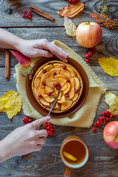 The woman's hands cut Apple pie on a wooden texture — Stock Photo, Image