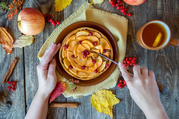 kadının elleri elmalı turta Ahşap dokusu üzerinde kesmek.