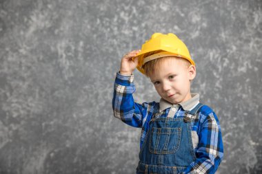Bir çocuk bir inşaat tutar kask ve gülümseyen