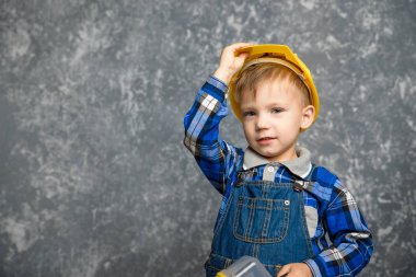 Bir çocuk bir inşaat tutar kask ve gülümseyen