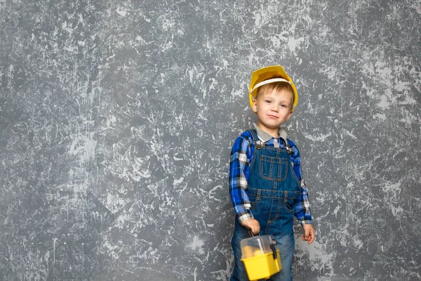 Le garçon en casque jaune et une boîte à outils jaune — Photo