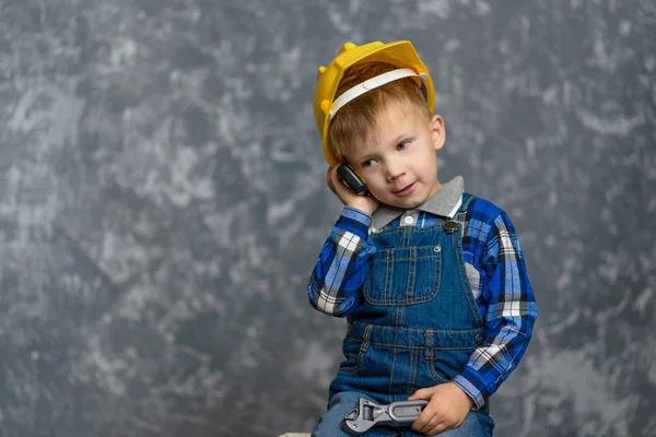 O menino-Construtor segura o telefone em suas mãos — Fotografia de Stock