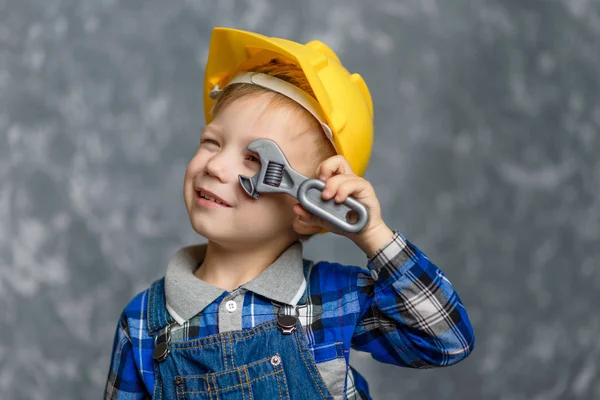 手にパイプレンチを保持している黄色のハード帽子の少年 — ストック写真