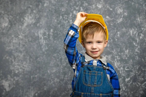 Bir çocuk bir inşaat tutar kask ve gülümseyen