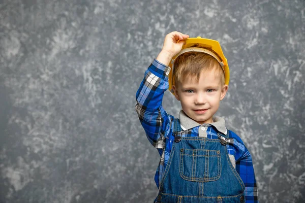 Bir çocuk bir inşaat tutar kask ve gülümseyen